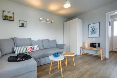 a living room with a gray couch and a table at Vouliagmeni Stylish Homes by BluPine in Athens