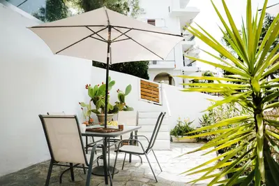 a patio with a table and chairs and an umbrella at Vouliagmeni Stylish Homes by BluPine in Athens