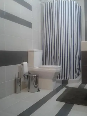 a bathroom with a toilet and a striped shower curtain at Super 36sqm Junior Suite in luxurious picturesque area in Piraeus