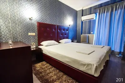 a bedroom with a large bed and a desk and blue curtains at Atlantic Hotel in Athens