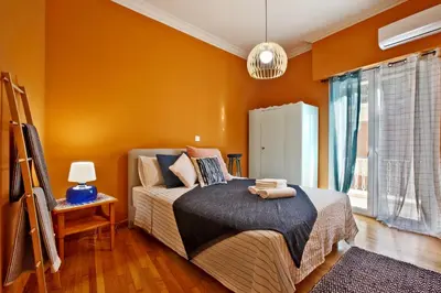 a bedroom with orange walls and a bed and a window at Athens Centre Apartment in Athens