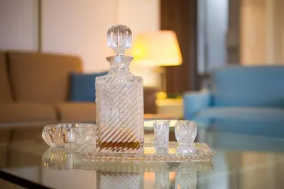 a glass bottle on a glass table with two glasses at Alexander's Penthouse in Athens
