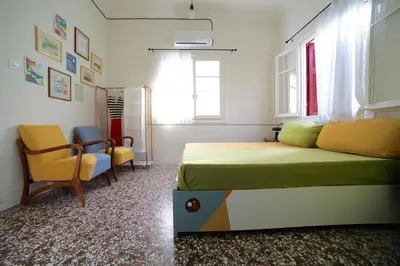 a bedroom with a bed and chairs and a window at Sun sto Spiti in Athens