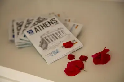 a book and three red roses on a table at Sun sto Spiti in Athens
