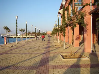 a street lined with trees on a sidewalk next to the water at Apartment near the Beach in Athens