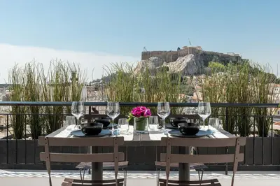 a table with wine glasses and flowers on a balcony at Executive 2 bdr Suite in Plaka - Acropolis view in Athens