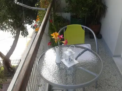a glass table on a balcony with a yellow chair at Medea in Athens