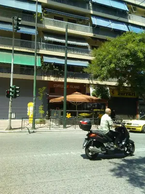 a man riding a motorcycle down a city street at Medea in Athens