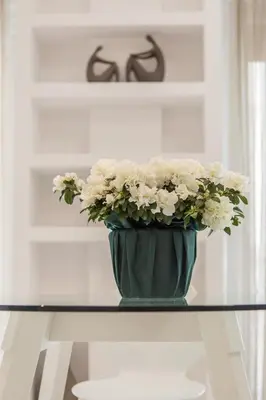 a green vase filled with white flowers on a table at Acropolis Museum - Modern Living [I] in Athens