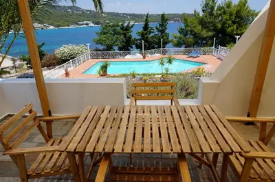 a wooden table and chairs on a patio with a swimming pool at Oneiro glico in Agia Marina Aegina