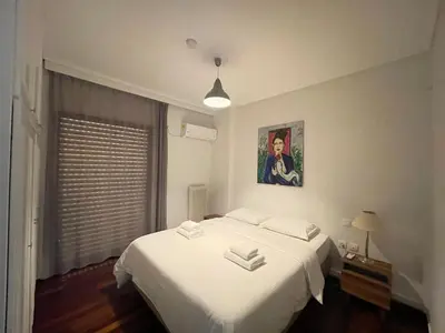 a bedroom with a white bed and a window at Aries - Glyfada City Center Apartment in Athens