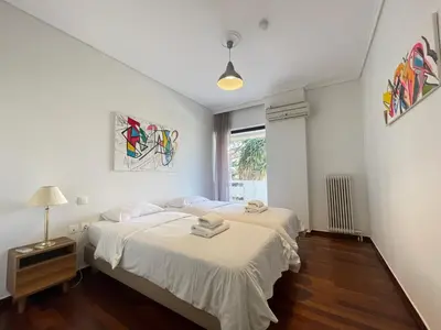 a white bedroom with a bed and a window at Aries - Glyfada City Center Apartment in Athens