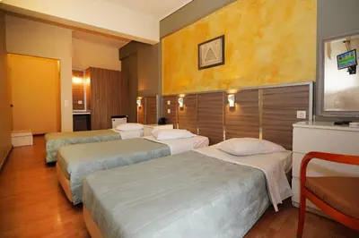 a hotel room with three beds and a television at Socrates Hotel in Athens