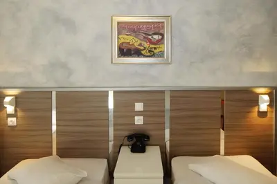 a room with two beds and a picture on the wall at Socrates Hotel in Athens