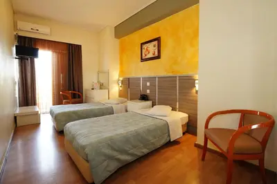 a hotel room with two beds and a chair at Socrates Hotel in Athens