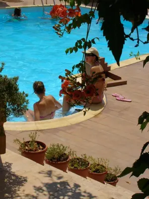 two people sitting in a swimming pool at Hotel Afea in Agia Marina Aegina