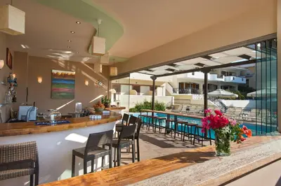 a restaurant with a bar and tables and chairs at Hotel Afea in Agia Marina Aegina