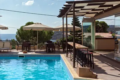 a pool with chairs and tables and umbrellas at Hotel Afea in Agia Marina Aegina