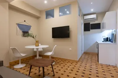 a living room with a table and chairs and a tv at Kolonaki Suites by Olala Homes in Athens