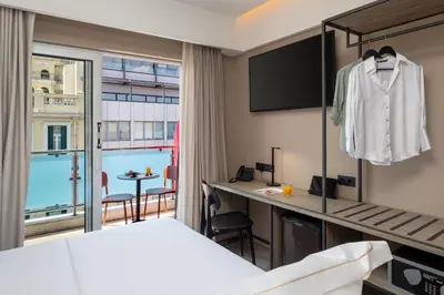 a hotel room with a bed and a desk and a window at Casual Kubic Athens in Athens