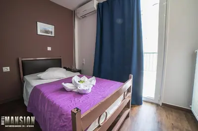 a bedroom with a bed with purple sheets and flowers on it at Mansion Hotel in Athens