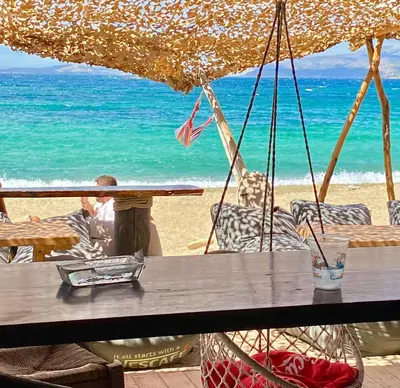 a table and chairs on a beach with the ocean at Villa Naya by the Beach in Anavissos