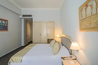 a bedroom with a white bed with a phone on it at Airotel Stratos Vassilikos Hotel in Athens
