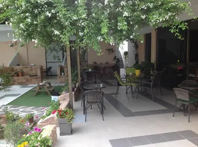 a patio with tables and chairs under a tree at Angela Hotel in Agia Marina Aegina