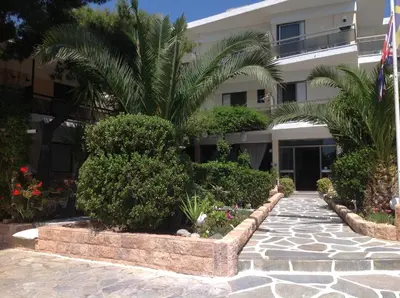 a building with a palm tree in front of it at Angela Hotel in Agia Marina Aegina