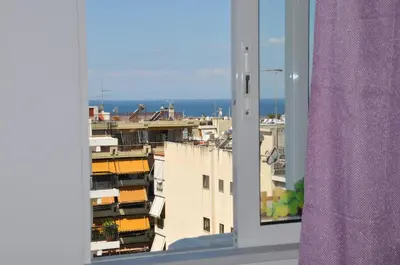 a view of the ocean from a window with a purple curtain at Your Home in Athens