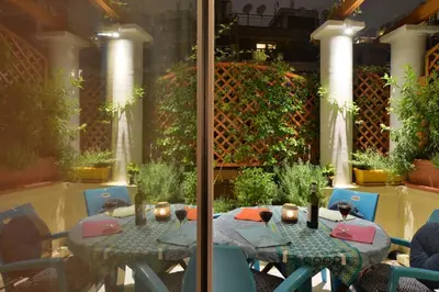 a table and chairs with wine bottles on it at Oasis veranda under columns.Kolonaki embassy area. in Athens