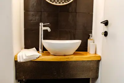 a bathroom with a white bowl sink on a wooden counter at we saw athens in Athens
