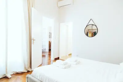 a white bedroom with two beds and a mirror at we saw athens in Athens