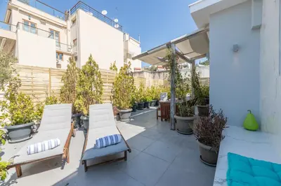 a patio with white chairs and potted plants at TOP Kolonaki Studio+Terrace Stunning Acropolis Views in Athens