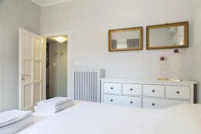 a white bedroom with a bed and a mirror at Beautiful Penthouse in Athens with outdoor jacuzzi in Athens