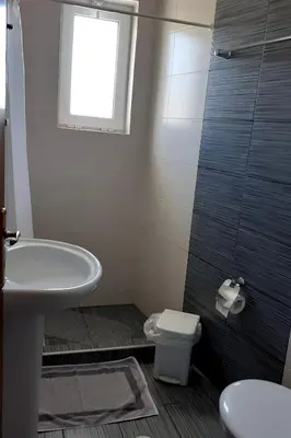 a bathroom with a sink and a toilet and a window at Nikolaki Rooms in Porto Rafti