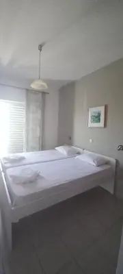 a large white bed in a room with a window at Nikolaki Rooms in Porto Rafti