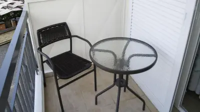 a glass table and a chair on a balcony at Nikolaki Rooms in Porto Rafti