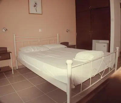 a white bed in a bedroom with a tiled floor at Nikolaki Rooms in Porto Rafti