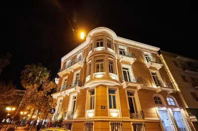 a large yellow building at night with a street at Exis Hotel in Athens