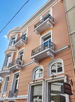 a pink building with white windows and balconies at Exis Hotel in Athens
