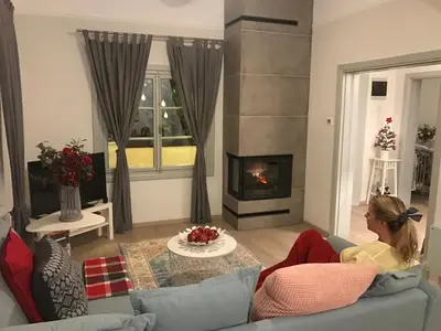 a woman sitting on a couch in a living room with a fireplace at Dina's House in Spáta