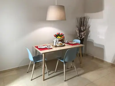 a dining room table with blue chairs and a table and a lamp at Dina's House in Spáta
