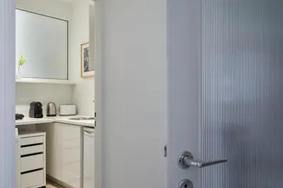 a kitchen with white cabinets and a door open at Parthenon Apartment in Athens