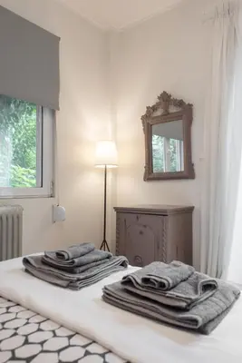 a white room with a bed with towels on it at Affordable luxury garden apartment in Athens