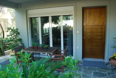 a porch with a wooden table and chairs and a door at Affordable luxury garden apartment in Athens
