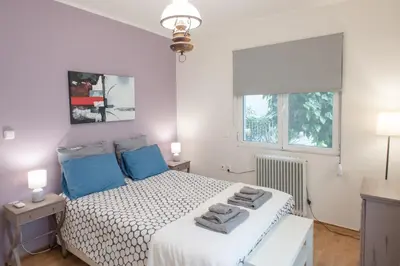 a bedroom with a bed with blue pillows on it at Affordable luxury garden apartment in Athens