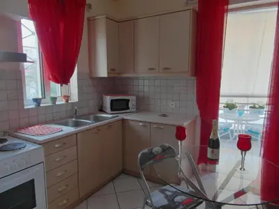 a kitchen with a sink and a microwave and red curtains at Athens Metro Mall Apart in Athens