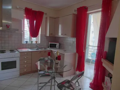 a kitchen with red curtains and a glass table at Athens Metro Mall Apart in Athens