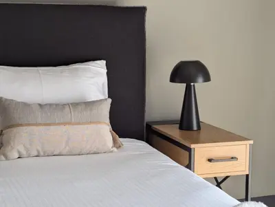 a bed with a black lamp on a night stand at Be My Guest Athens in Athens